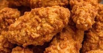 Crispy fried chicken tenders served hot with golden crunchy coating, dipping sauces, parsley, and a side of garlic mayo.