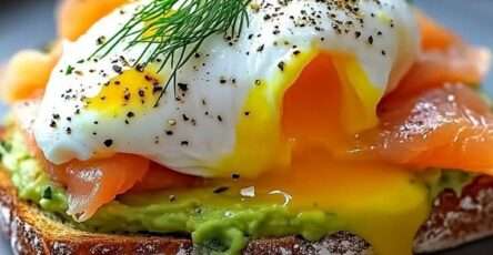 Avocado toast topped with smoked salmon, poached egg, fresh dill, black pepper, chili flakes, lemon, and crispy sourdough bread.