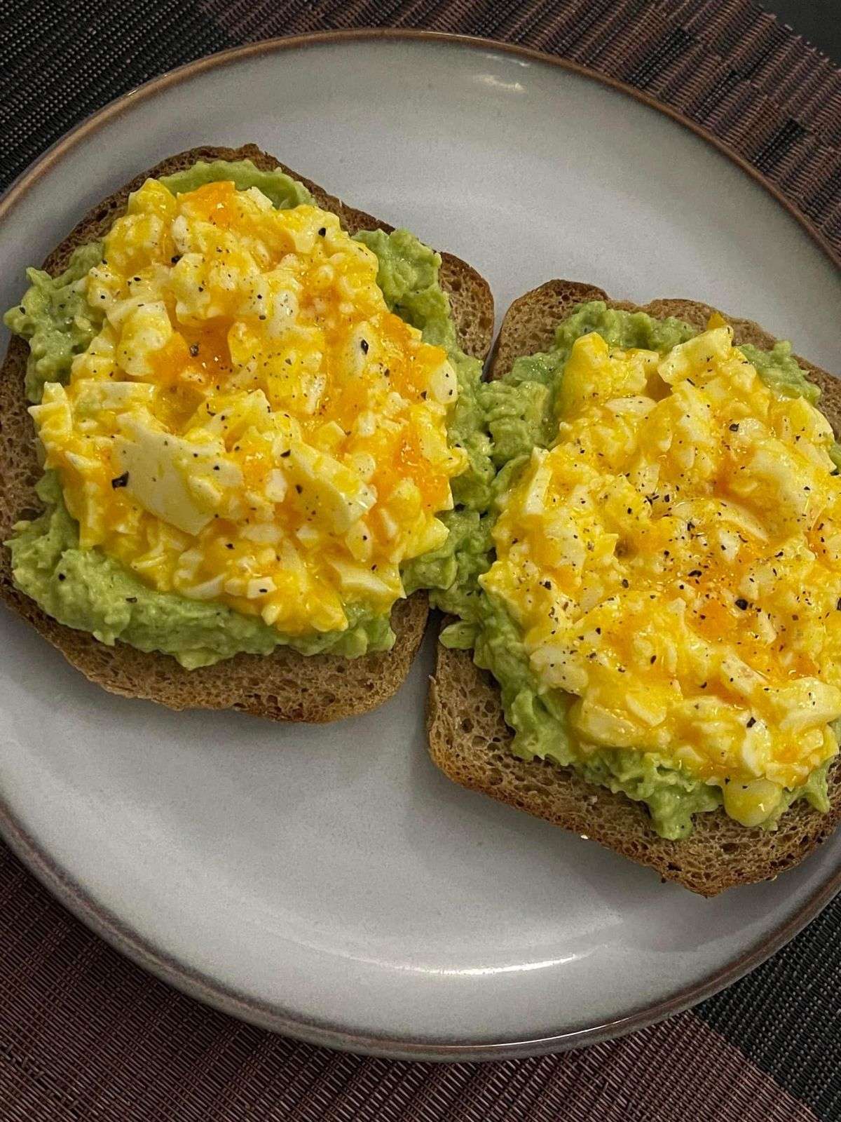 Crispy avocado egg toast made with mashed avocado, chunky chopped boiled eggs, whole grain bread, black pepper, chili flakes, and fresh lemon flavor.