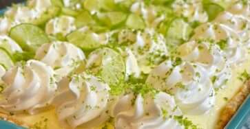 Sugar-free key lime cream dessert sliced into squares with graham cracker crust, creamy filling, tangy key lime layer, whipped topping, and lime zest garnish.