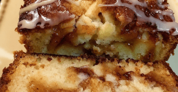 A sliced glazed apple cinnamon loaf cake with diced apples, cinnamon swirl filling, vanilla glaze, and a moist golden crumb on a serving plate.