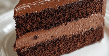 A rich chocolate layer cake with moist cocoa layers, creamy chocolate filling, glossy ganache frosting, and chocolate shavings on top.