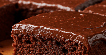 Fudgy chocolate cake with glossy dark chocolate ganache, moist chocolate crumb, clean square slices, and a rich homemade texture.