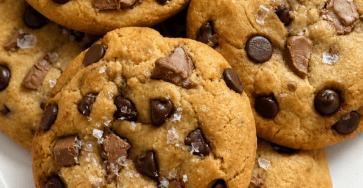 Soft chocolate chip cookies with golden edges, gooey chocolate chips, chopped chocolate pieces, and flaky sea salt on top.