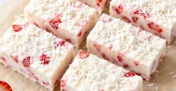 Strawberry coconut frozen yogurt bars cut into squares with creamy Greek yogurt, fresh strawberry pieces and shredded coconut on top.