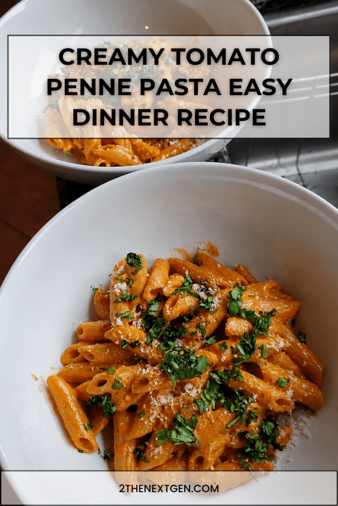 A bowl of creamy tomato penne pasta coated in a smooth pink tomato cream sauce, topped with grated parmesan and fresh basil.