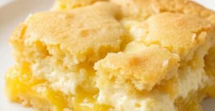 A warm sugar-free lemon cream cheese dump cake baked in a rectangular dish with golden cake topping, bubbling lemon filling, and creamy cheese pockets.