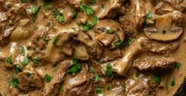 Tender sliced beef in a creamy mushroom mustard sauce with onions, garlic, thyme, and fresh parsley served hot in a rustic dish.
