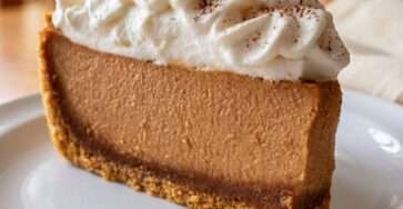 A sliced sugar-free espresso chocolate layer cheesecake with almond crust, creamy coffee cheesecake filling, dark cocoa layer, whipped cream topping, and cocoa dusting.