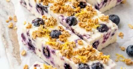Blueberry lemon frozen yogurt bars cut into squares with creamy yogurt, whole blueberries, lemon zest and crunchy granola topping.