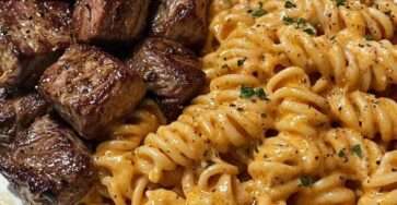 Juicy seared steak bites served beside creamy garlic Parmesan rotini pasta, finished with fresh parsley and cracked black pepper.