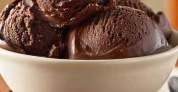 A bowl of sugar-free chocolate cottage cheese ice cream with a creamy dark chocolate texture, chocolate chips, and smooth scoops served cold.