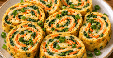 Sliced vegetable rolled omelet filled with melted cheese, spinach, grated carrot, and scallions, arranged in colorful bite-size rounds for a healthy lunchbox.